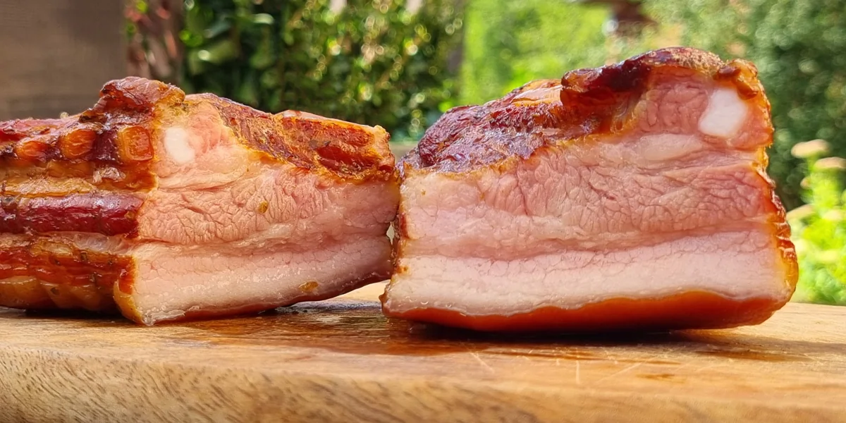 Geräucherter Schweinebauch halbiert auf einem Holzbrett