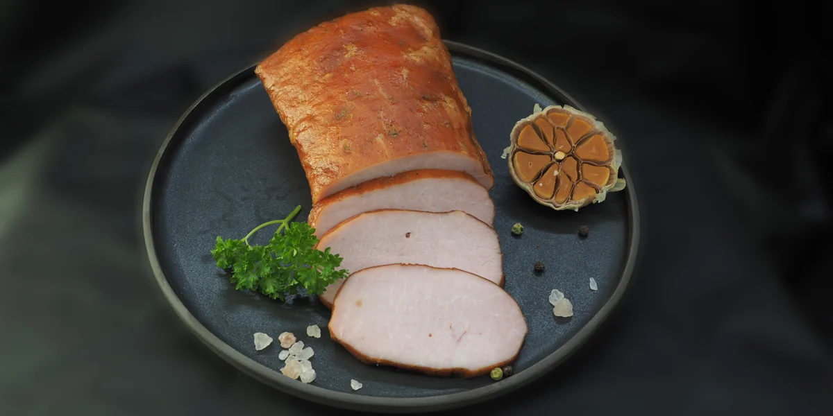 Aufgeschnittene geräucherte Schweinelende auf einem dunklen Teller