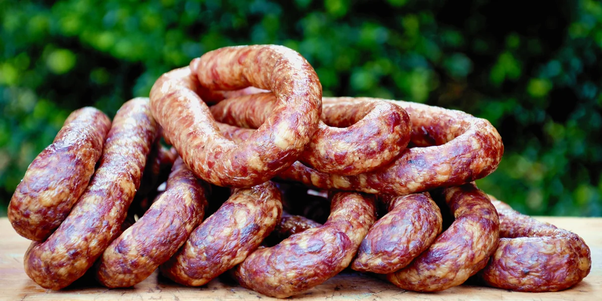 Geräucherte Würste auf einem Holzbrett im Garten